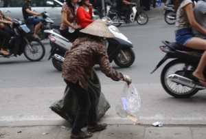 Một phụ nữ nhặt bao ni lông rơi vãi trên đường phố Hà Nội để bán kiếm ít tiền sống qua ngày.
